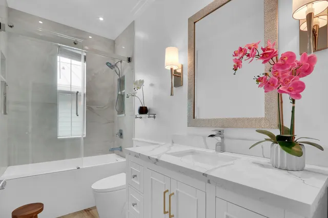 a bathroom with a granite countertop shower sink vanity mirror and toilet