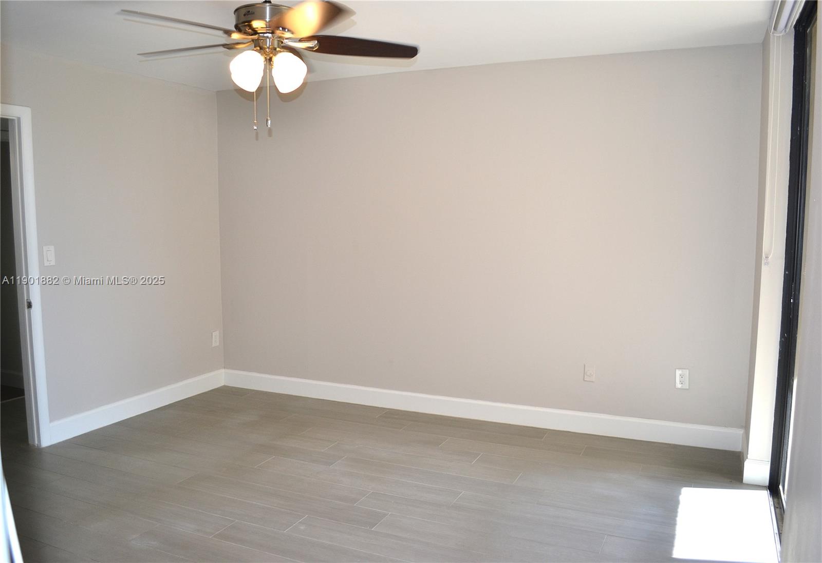 8045 Southwest 107th Avenue, Unit 303 Miami, FL 33173 - Photo 17 of 26 an empty room with a chandelier fan and wooden floor