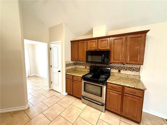 a kitchen with stainless steel appliances granite countertop a stove a sink and a refrigerator
