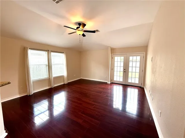 a view of empty room with wooden floor and fan