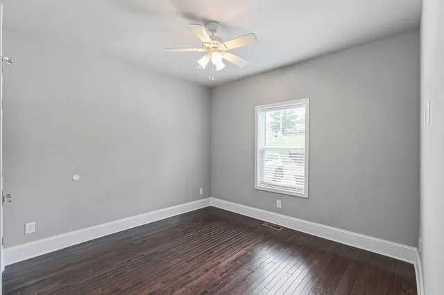 an empty room with wooden floor and window