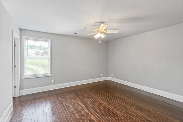 an empty room with wooden floor and window