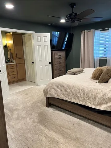 a bedroom with a large bed a flat tv screen and dresser