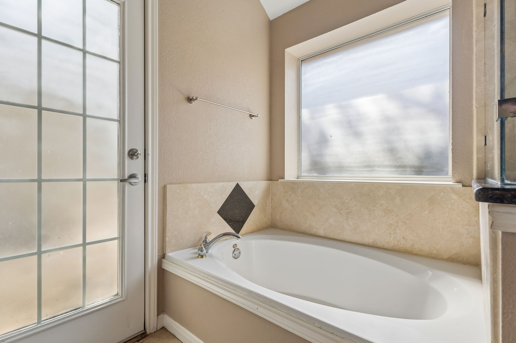 15814 Rustic Lane Austin, TX 78717 - Photo 25 of 29 Natural light pours over a deep soaking tub surrounded by elegant tile details.