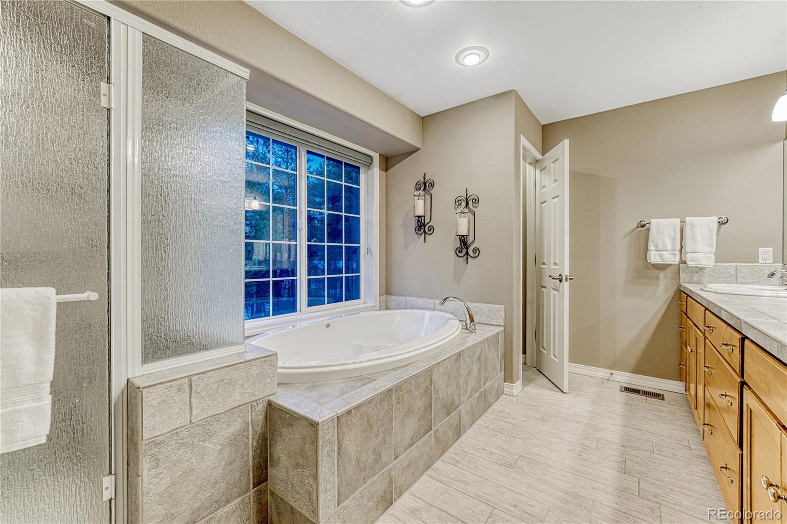 18150 Bakers Farm Road Colorado Springs, CO 80908 - Photo 22 of 49 a bathroom with a tub a sink and a large mirror