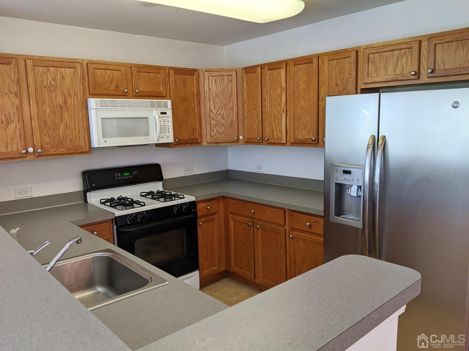 358 Rector Street, Unit 504 Perth Amboy, NJ 08861 - Photo 5 of 18 a kitchen with stainless steel appliances granite countertop a refrigerator a stove and a sink with wooden cabinets