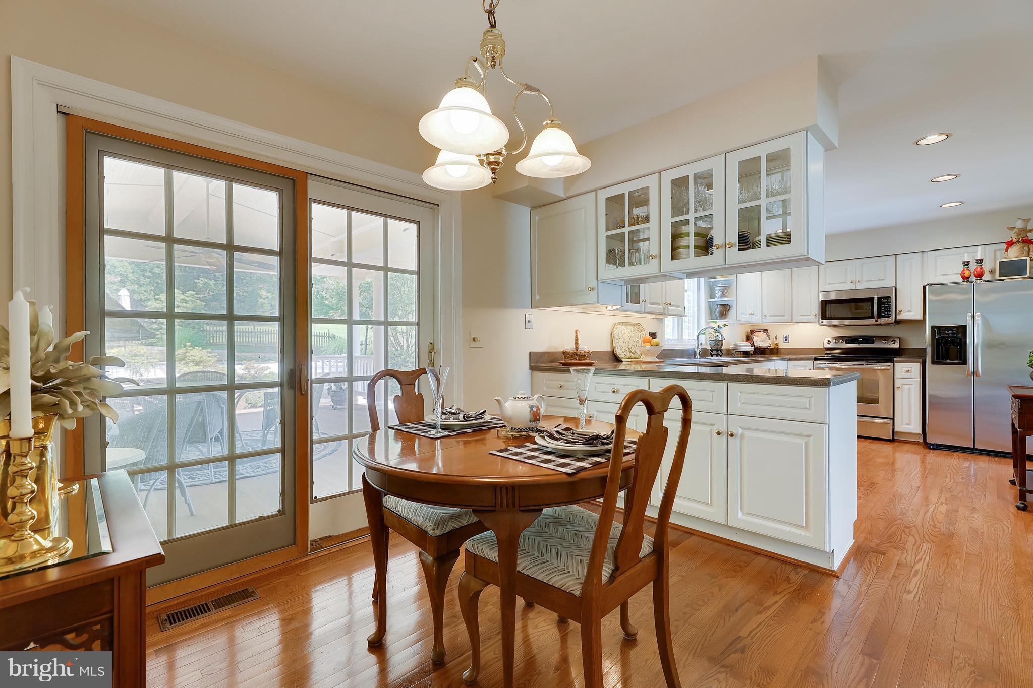 13402 Cambria Farms Road Phoenix, MD 21131 - Photo 13 of 28 a dining room with wooden floor a chandelier a glass table and chairs