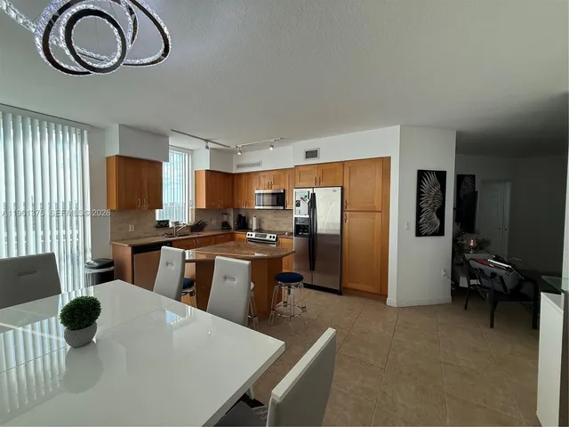 a kitchen with stainless steel appliances a table chairs and a refrigerator