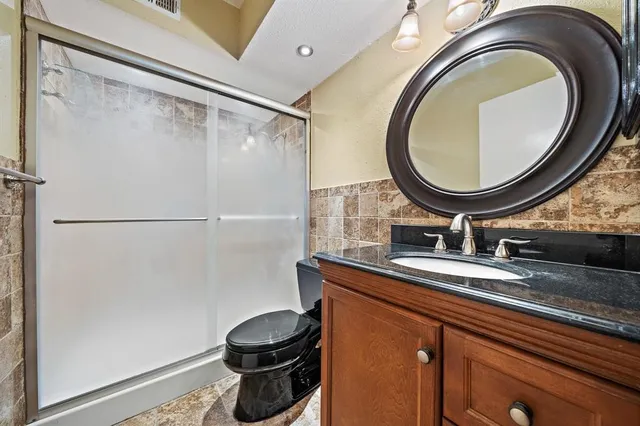 a bathroom with a granite countertop sink a toilet and a mirror