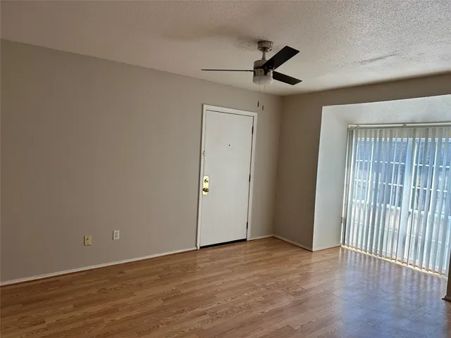 an empty room with wooden floor fan and windows