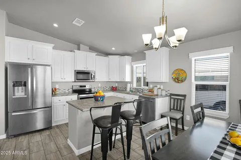 a kitchen with stainless steel appliances a stove a refrigerator a microwave a dining table and chairs with wooden floor