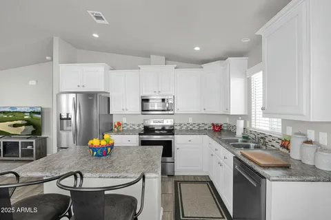 a kitchen that has a sink cabinets and stainless steel appliances