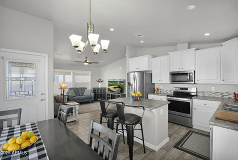 a kitchen with stainless steel appliances granite countertop a stove top oven a sink a stove a dining table and chairs with wooden floor