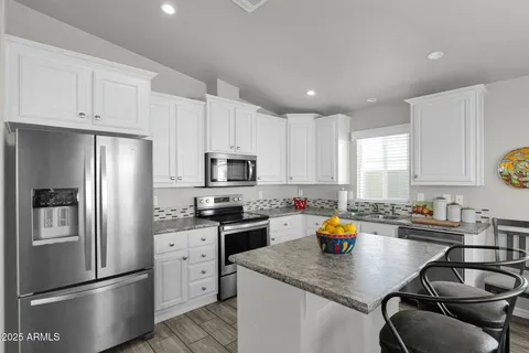 a kitchen with stainless steel appliances granite countertop a sink a stove a refrigerator a stove a dining table and chairs