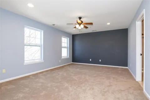an empty room with windows and chandelier fan