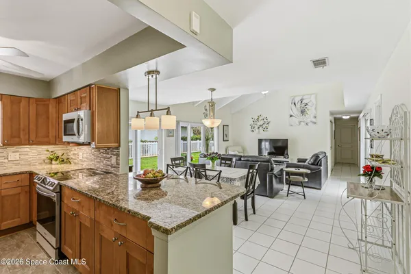 a kitchen with stainless steel appliances granite countertop a sink a refrigerator a washer and dryer with wooden floor