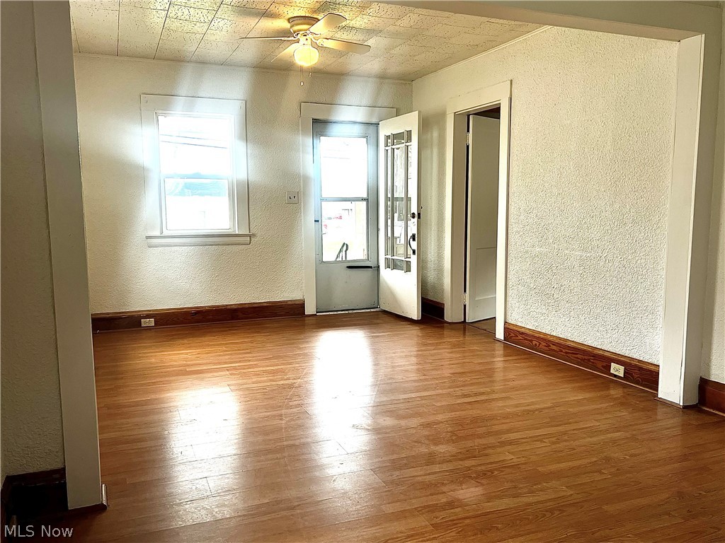 67 Forbes Road Bedford, OH 44146 - Photo 5 of 20 Unfurnished room with a textured wall, dark wood-style flooring, and a ceiling fan