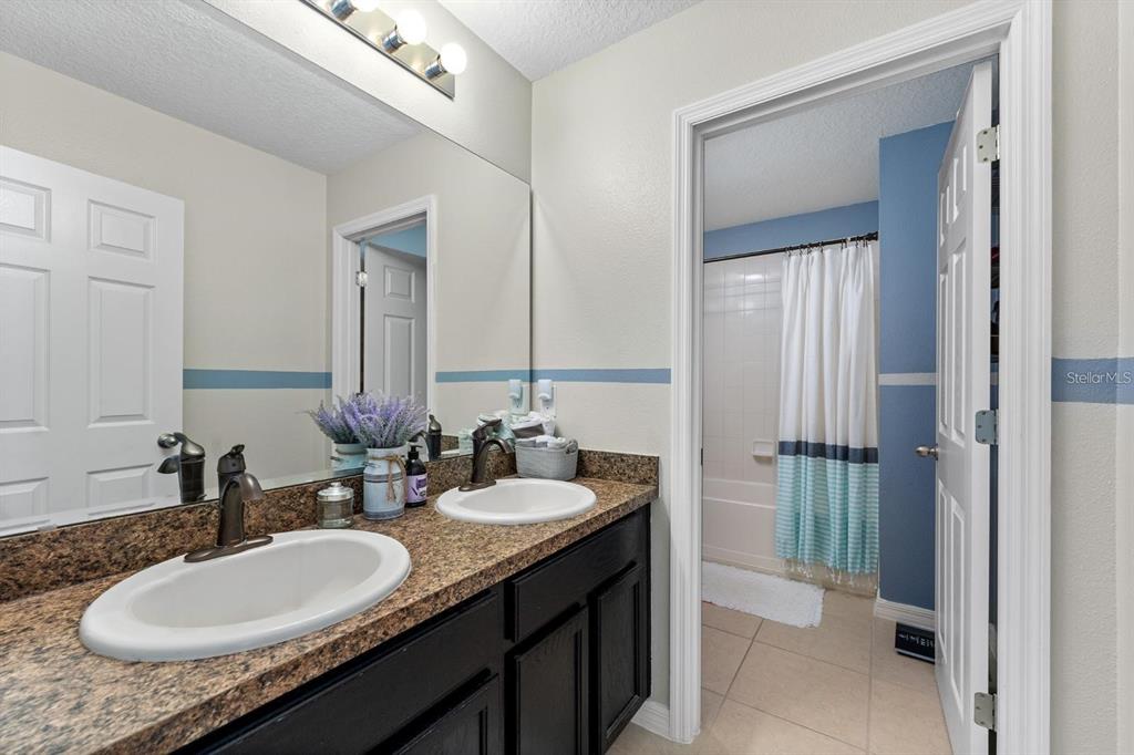 754 Andalusia Loop Davenport, FL 33837 - Photo 12 of 28 a bathroom with a granite countertop sink and a mirror
