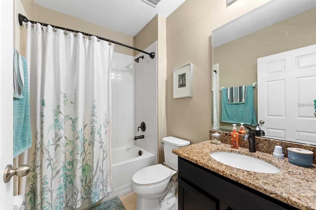 754 Andalusia Loop Davenport, FL 33837 - Photo 19 of 28 a bathroom with a granite countertop sink toilet and a mirror