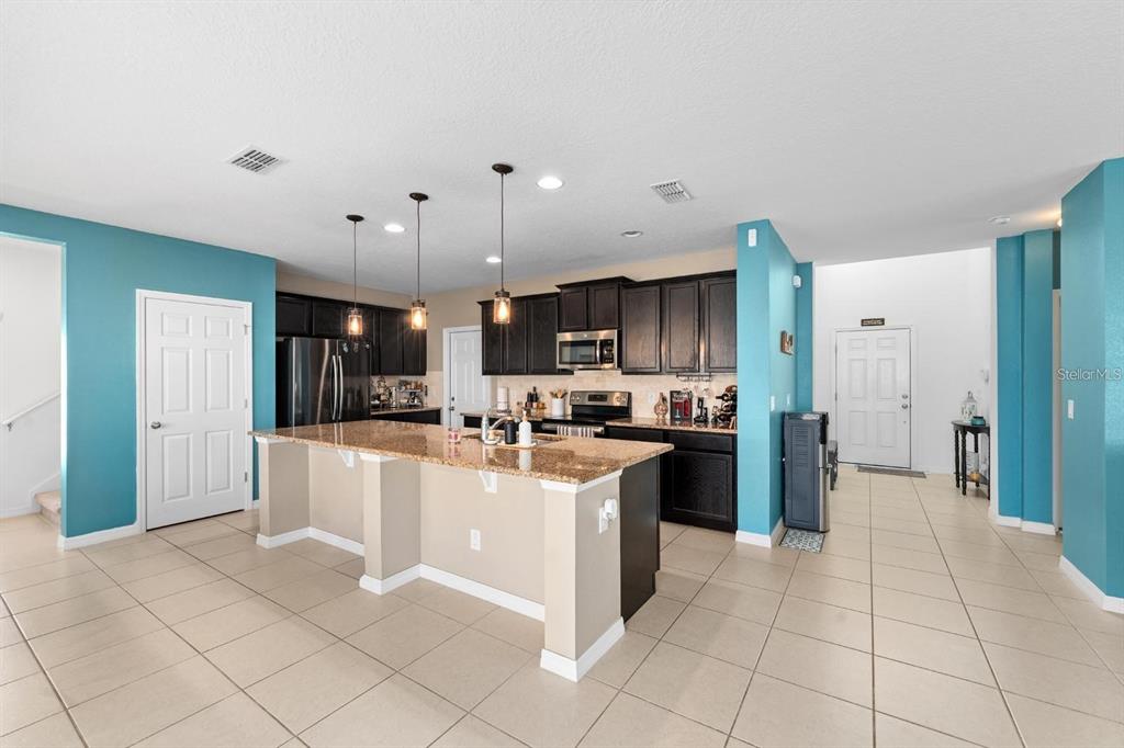 754 Andalusia Loop Davenport, FL 33837 - Photo 7 of 28 a large kitchen with stainless steel appliances kitchen island granite countertop a refrigerator and a sink