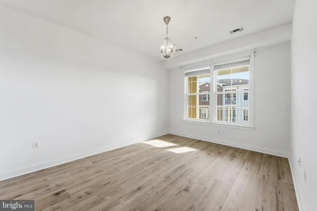 a view of a hallway with wooden floor and a chandelier