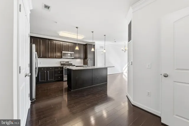 a kitchen with kitchen island granite countertop a refrigerator and a sink