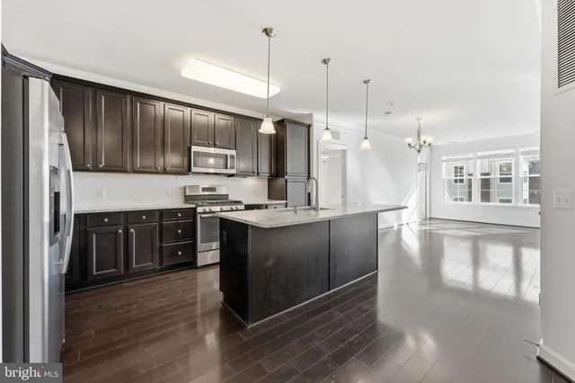 a kitchen with stainless steel appliances granite countertop a stove a sink and a refrigerator with wooden floor