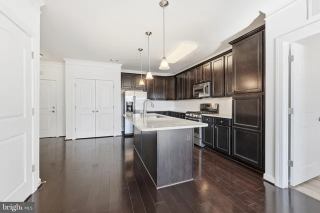 a kitchen with kitchen island wooden floors appliances and cabinets