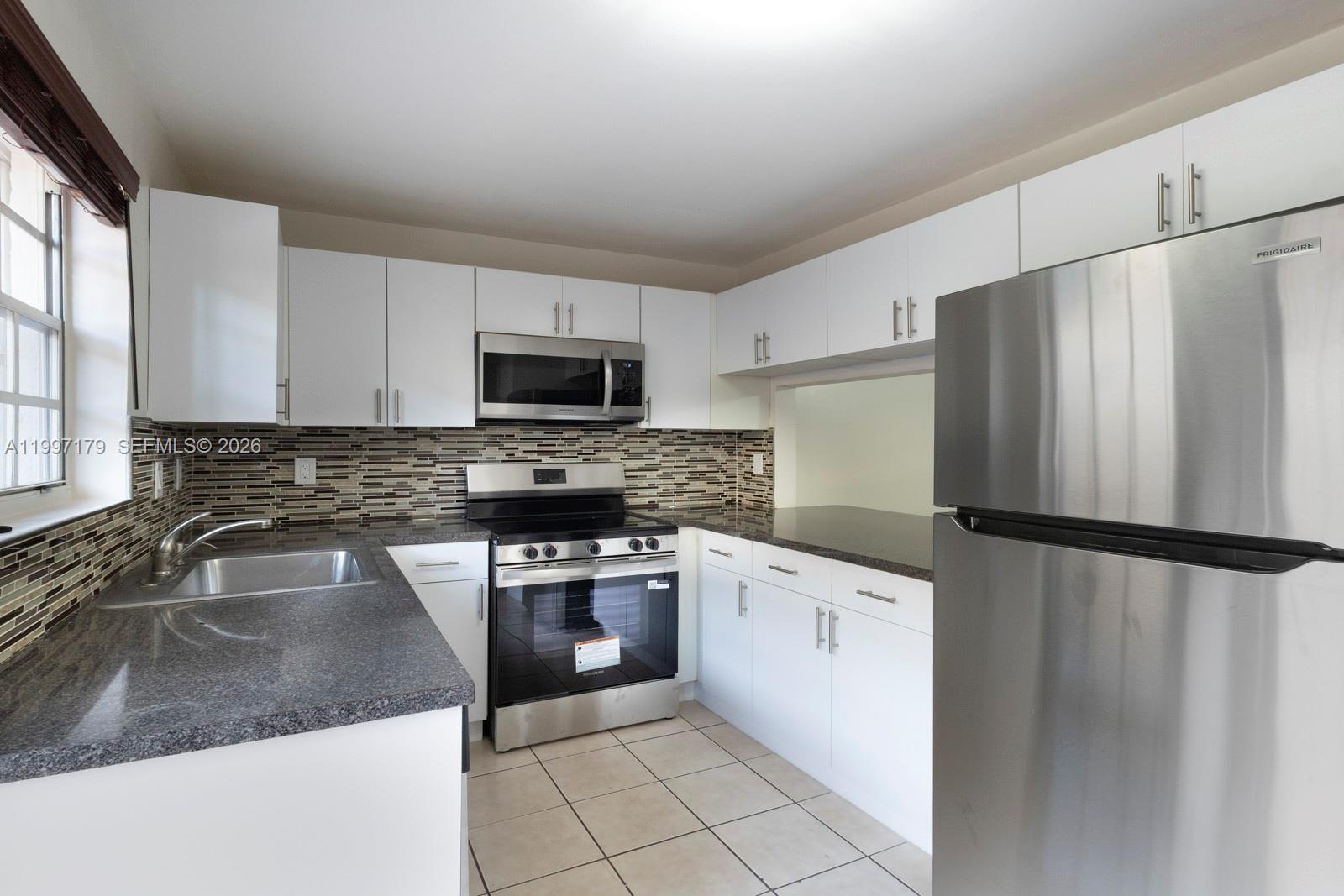 a kitchen with granite countertop a refrigerator and a sink