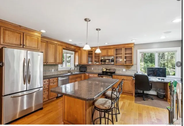 a kitchen with stainless steel appliances granite countertop a stove a refrigerator a kitchen island a dining table and chairs with wooden floor