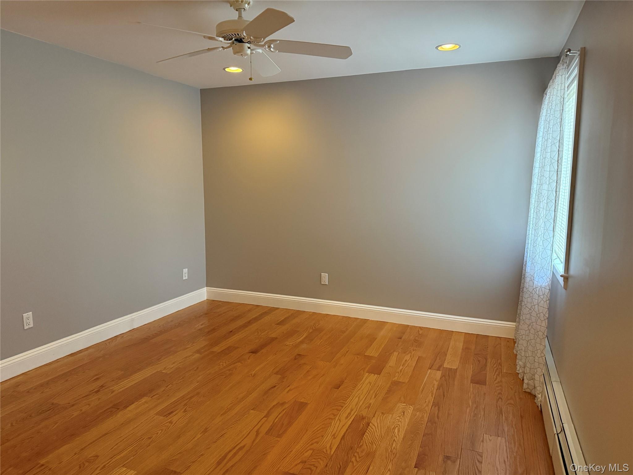 1926 Midlane Road Syosset, NY 11791 - Photo 6 of 21 an empty room with wooden floor and fan