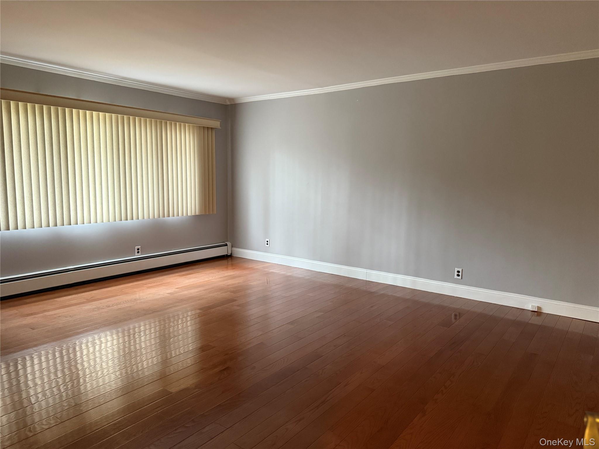 1926 Midlane Road Syosset, NY 11791 - Photo 9 of 21 an empty room with wooden floor and windows with curtains