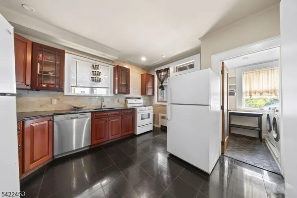 a kitchen with a refrigerator a stove a sink and a oven with wooden floor