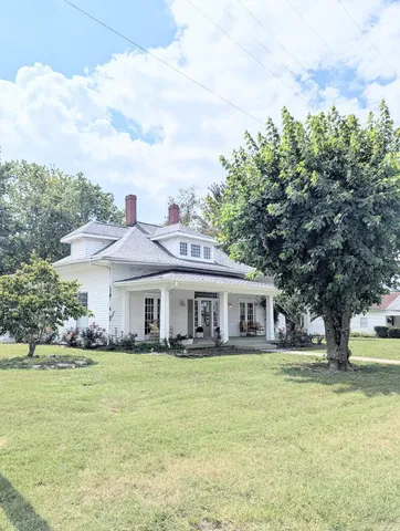 a view of house with a big yard and large trees