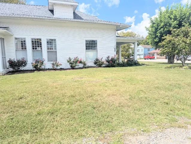 a front view of house with yard and trees in the background