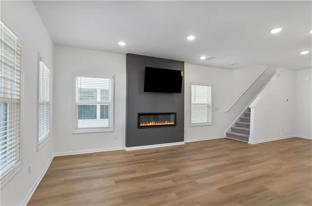 an empty room with windows fireplace and wooden floor
