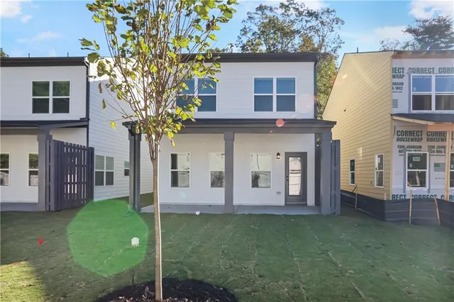 a view of house in front of a big yard with large trees