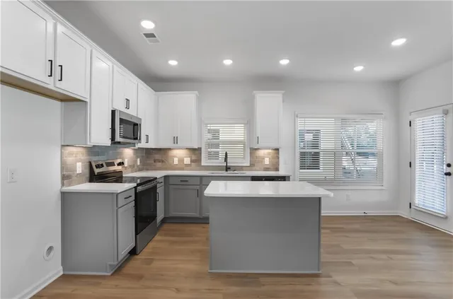 a kitchen with kitchen island granite countertop a sink cabinets and wooden floor