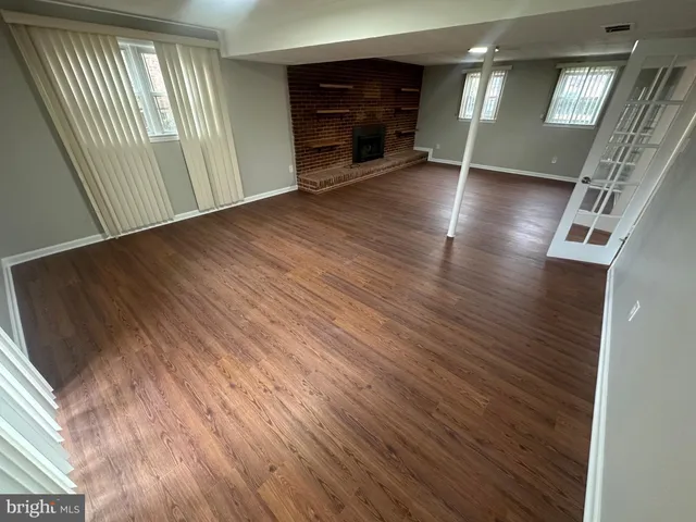 a view of an empty room with wooden floor and a fireplace
