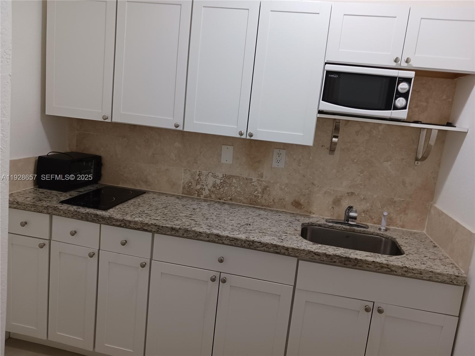 650 Southwest 44th Court Miami, FL 33134 - Photo 8 of 12 a kitchen with granite countertop white cabinets and a sink