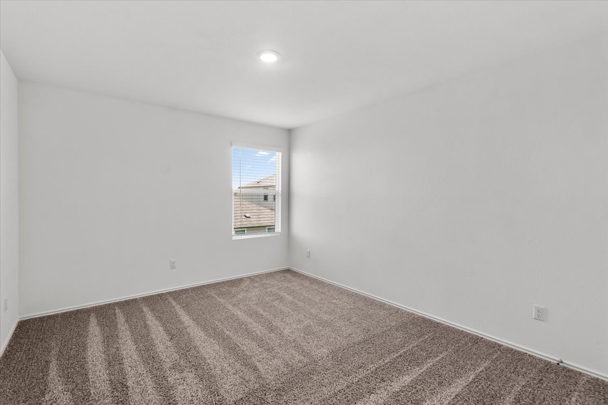 448 Perfect World Loop Jarrell, TX 76537 - Photo 34 of 40 A well-lit, quiet bedroom retreat with plush carpet flooring, ready for personalization.