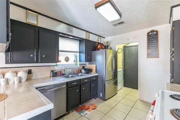 a kitchen with stainless steel appliances kitchen island granite countertop a refrigerator and a sink