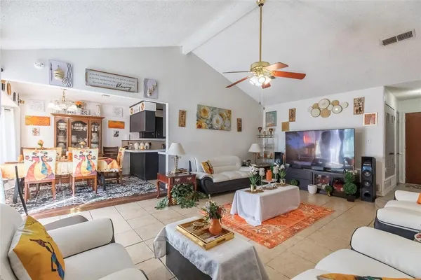 a living room with furniture kitchen view and a chandelier