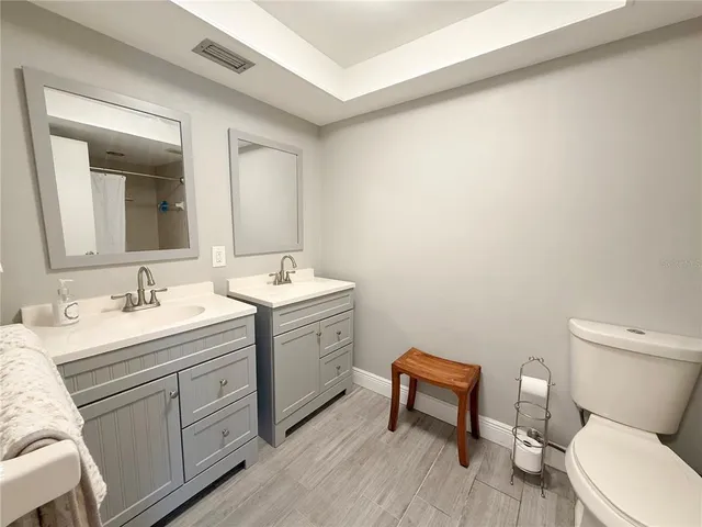a bathroom with a toilet sink double vanity and mirror