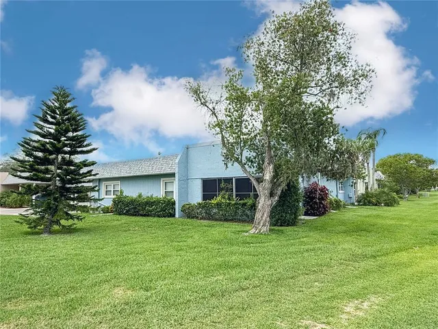 a view of house in front of a big yard with large trees