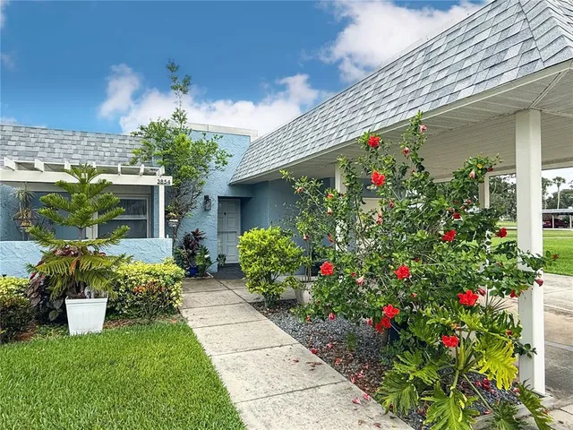 a front view of a house with a porch and a lots of flower garden