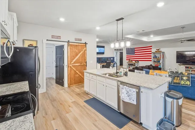 a kitchen with granite countertop a stove a sink dishwasher and a refrigerator with wooden floor