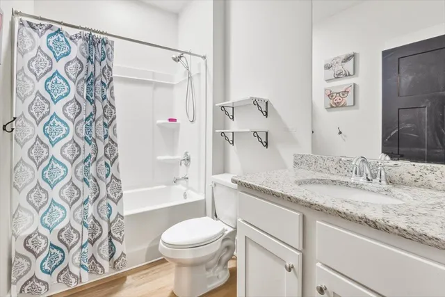 a bathroom with a granite countertop sink toilet and shower