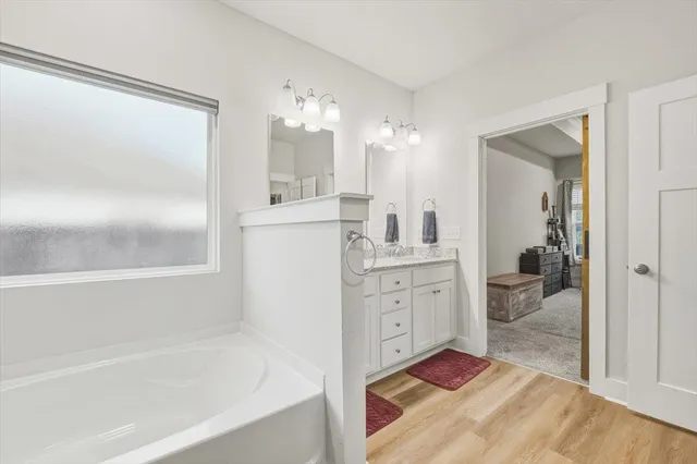 a spacious bathroom with a double vanity sink a mirror and a bathtub
