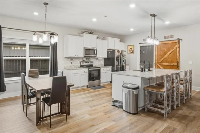 a kitchen with stainless steel appliances a dining table chairs stove and refrigerator